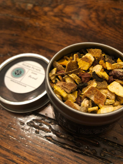 KC Tea Company's Golden Pu-Erh Tea in a silver tin on a wood background